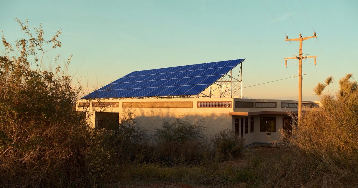 Solar panels on an Indian house beside an electricity distribution pole at golden hour