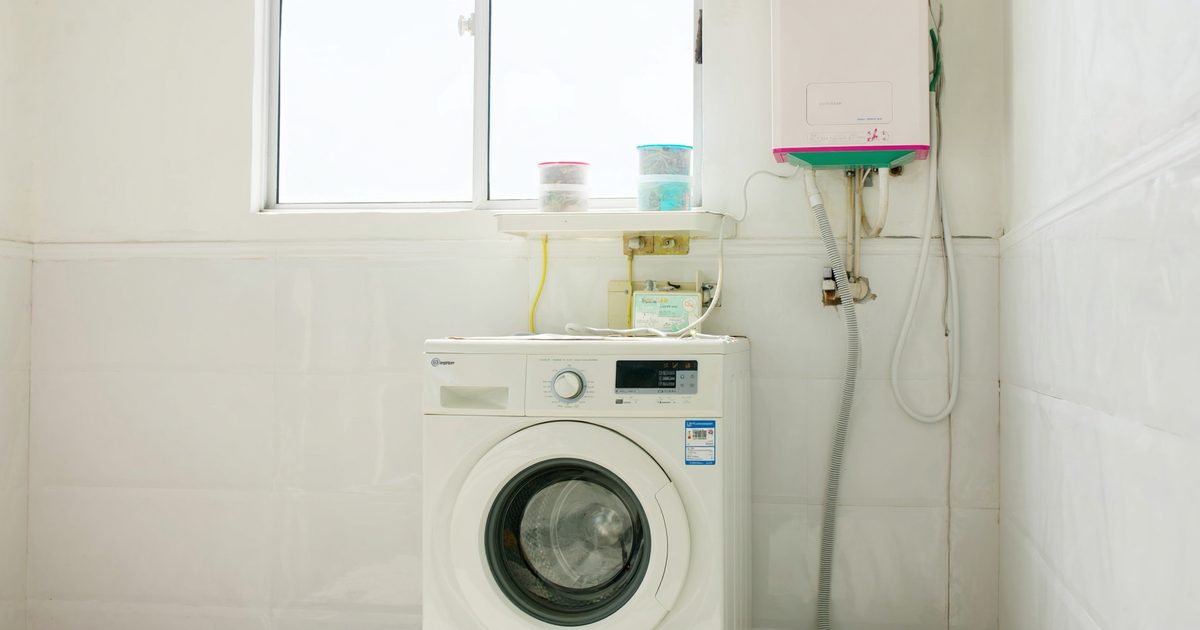 A washing machine and wall-mounted electric water heater in the utility area of an Indian home