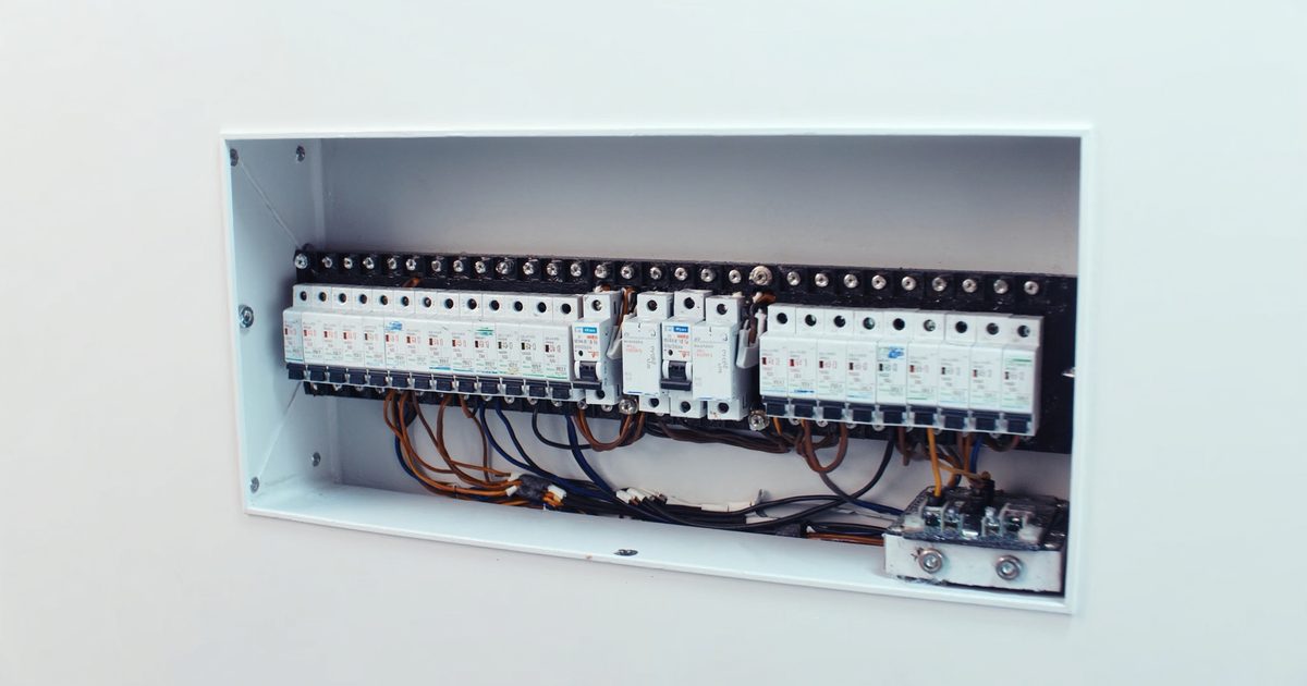 An open household distribution board with rows of circuit breakers on a DIN rail