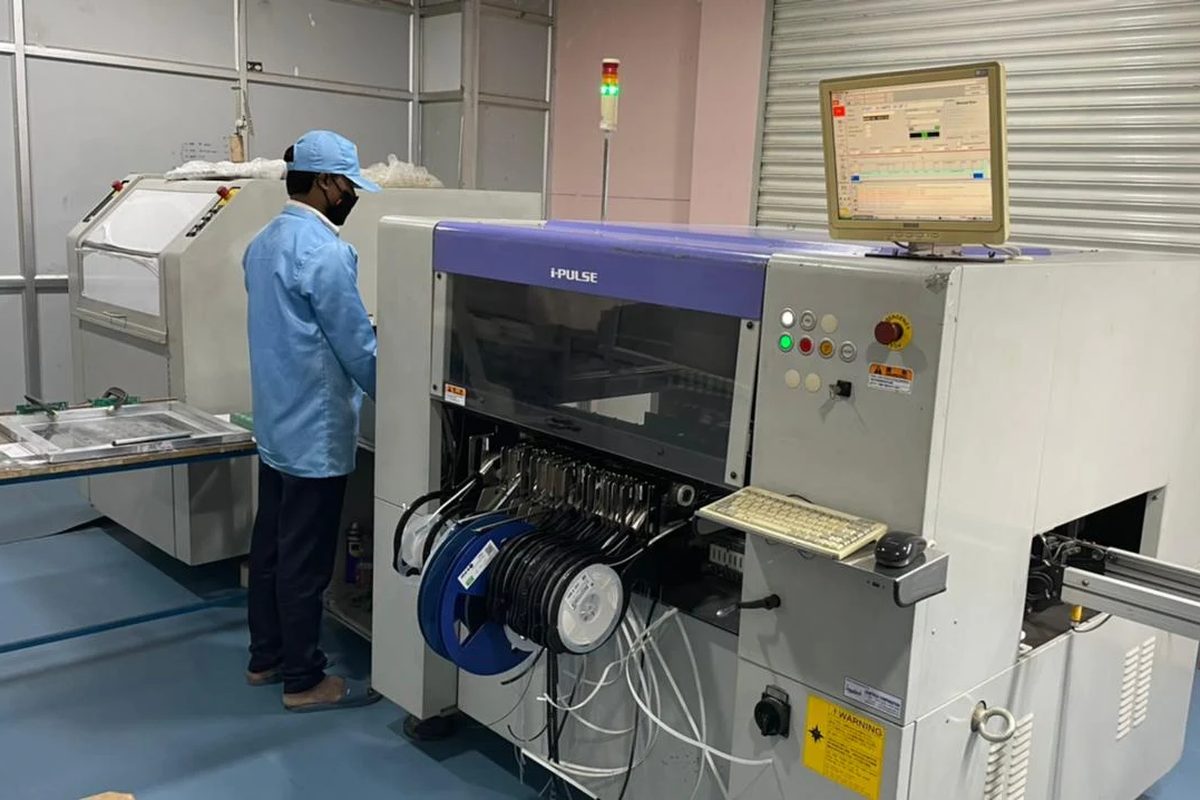 An operator at a surface-mount placement machine with component reels loaded